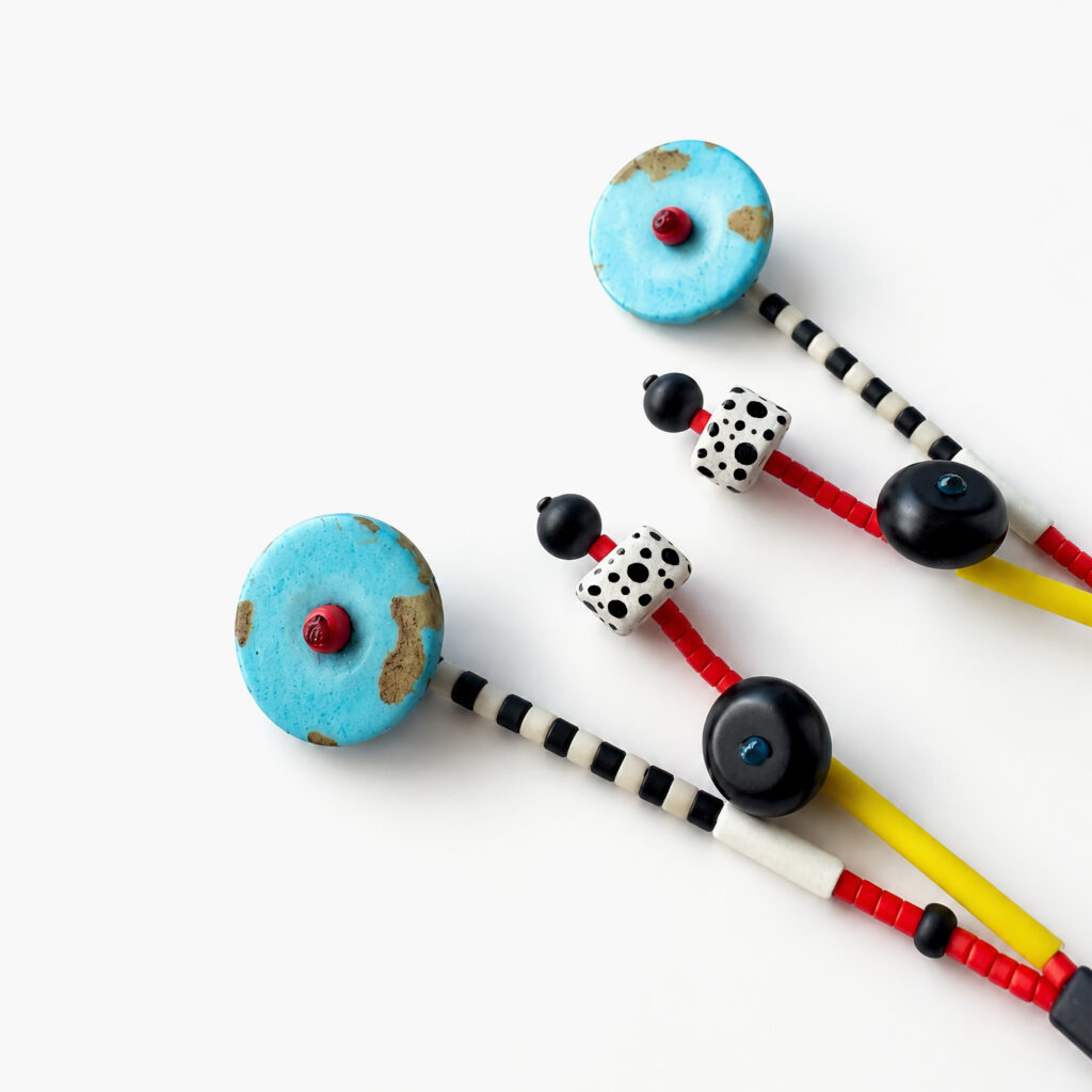 Close-up of turquoise beaded earrings showing striped and polka-dot details