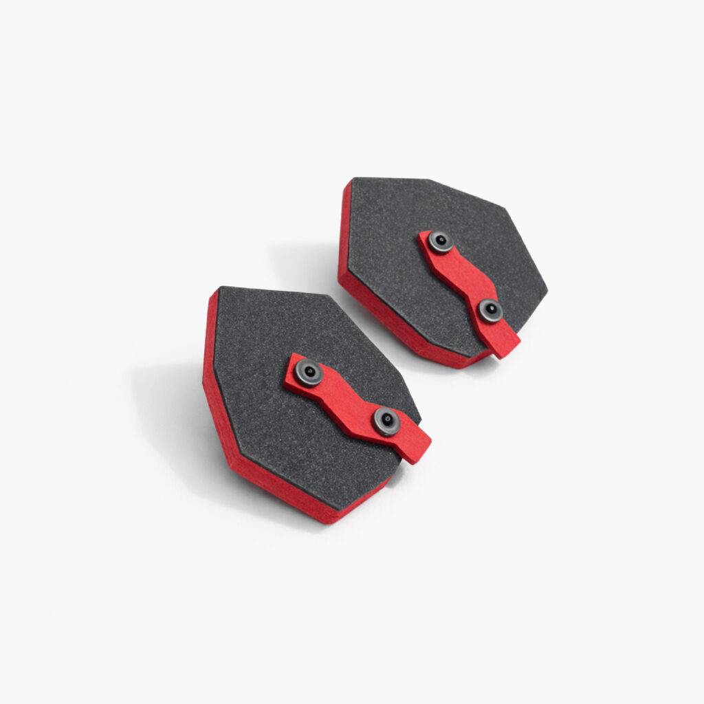 Angled view of black red industrial geometric wooden earrings showing their layered red details