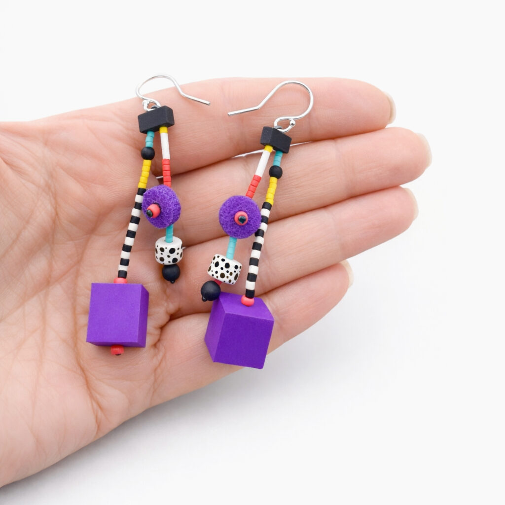 Purple pop art geometric dangle earrings with colorful beads and wooden cubes shown in hand