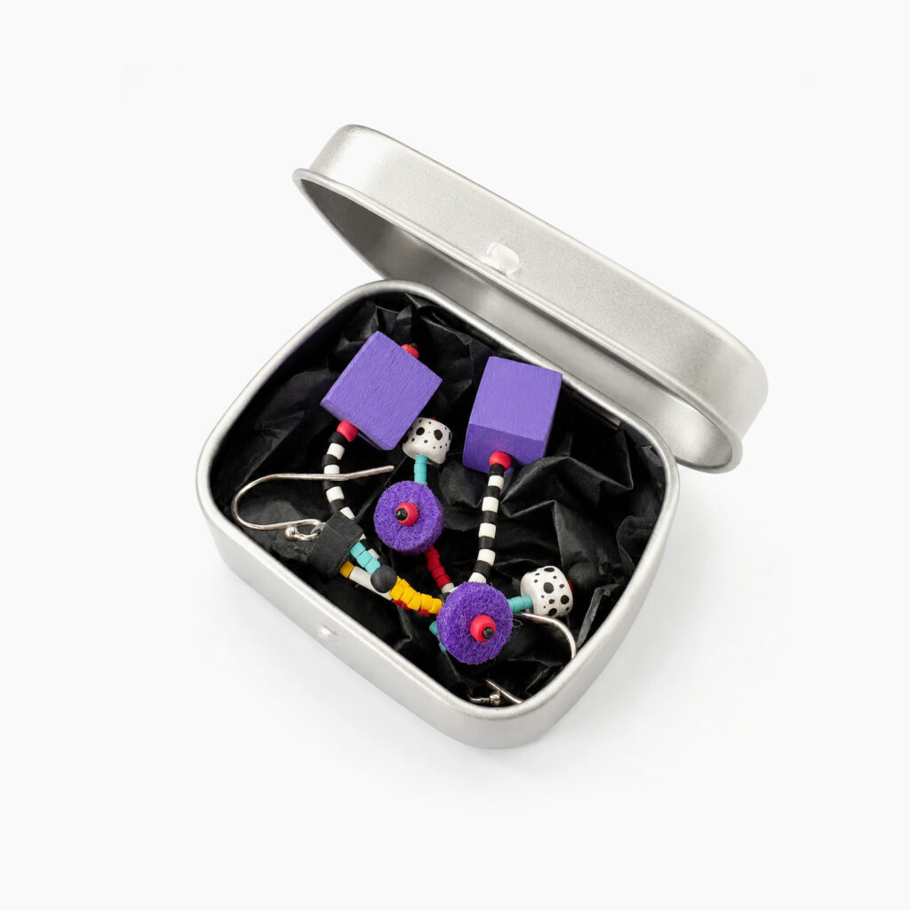 Purple beaded dangle earrings with geometric wooden elements displayed in a metal gift box