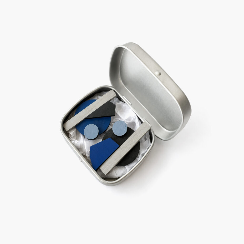 1. Blue and black geometric statement earrings displayed in a metal gift box