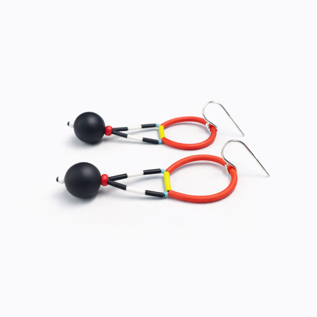 Pair of red and black geometric beaded earrings arranged on white background