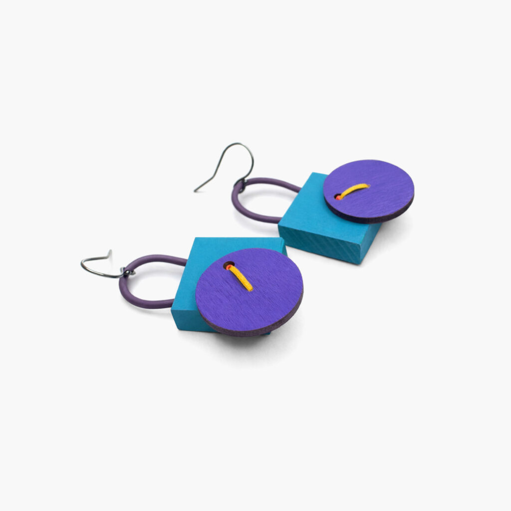 Purple and petrol statement earrings with circular wooden elements – angled view