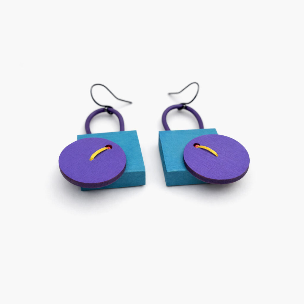 Pair of purple and petrol geometric dangle earrings on white background