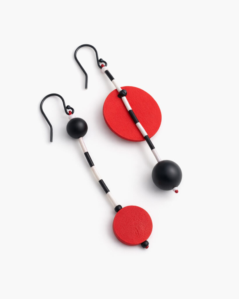 Mismatched statement earrings with red wooden discs and black bead details