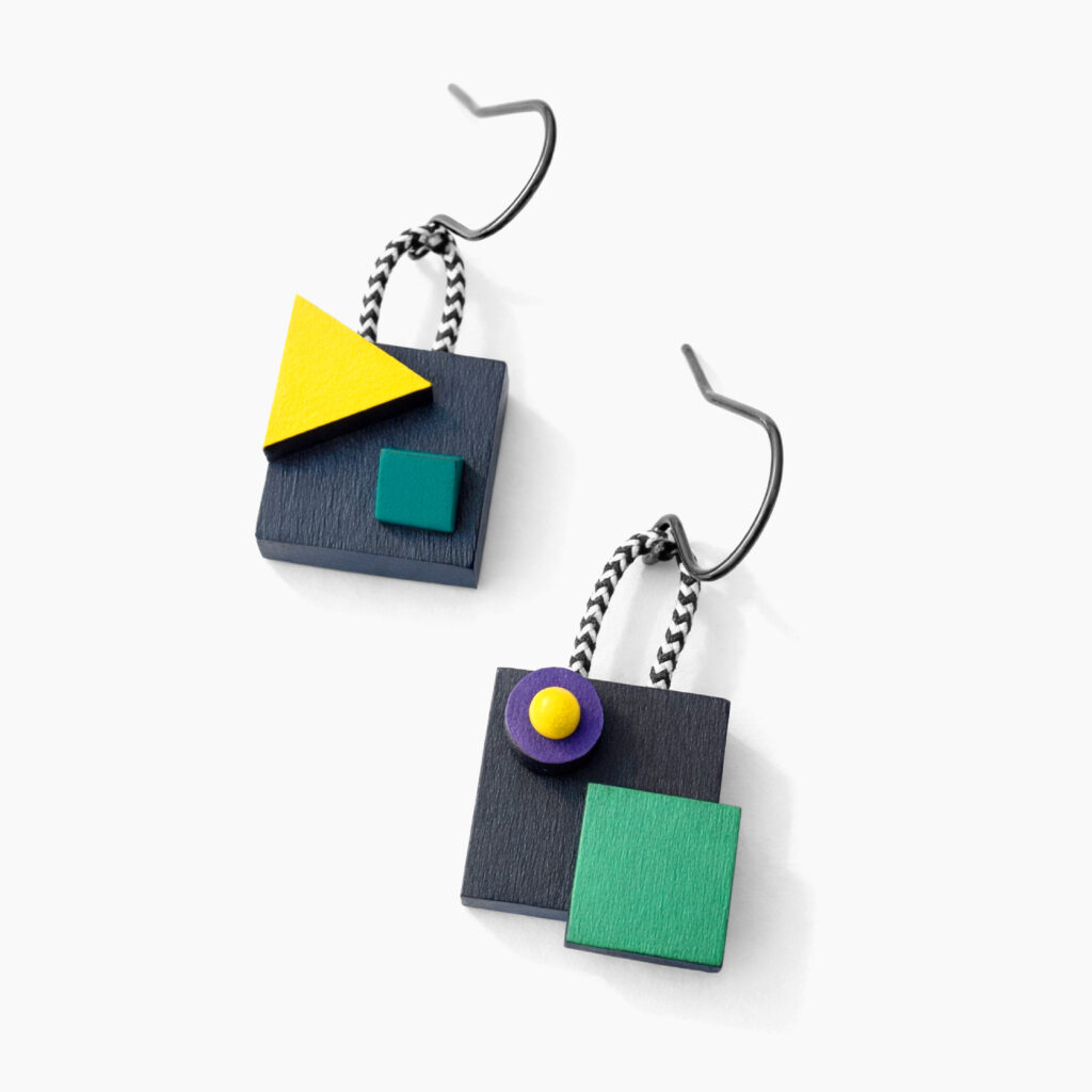 Colorful mismatched wooden earrings with contrasting geometric shapes on a white background