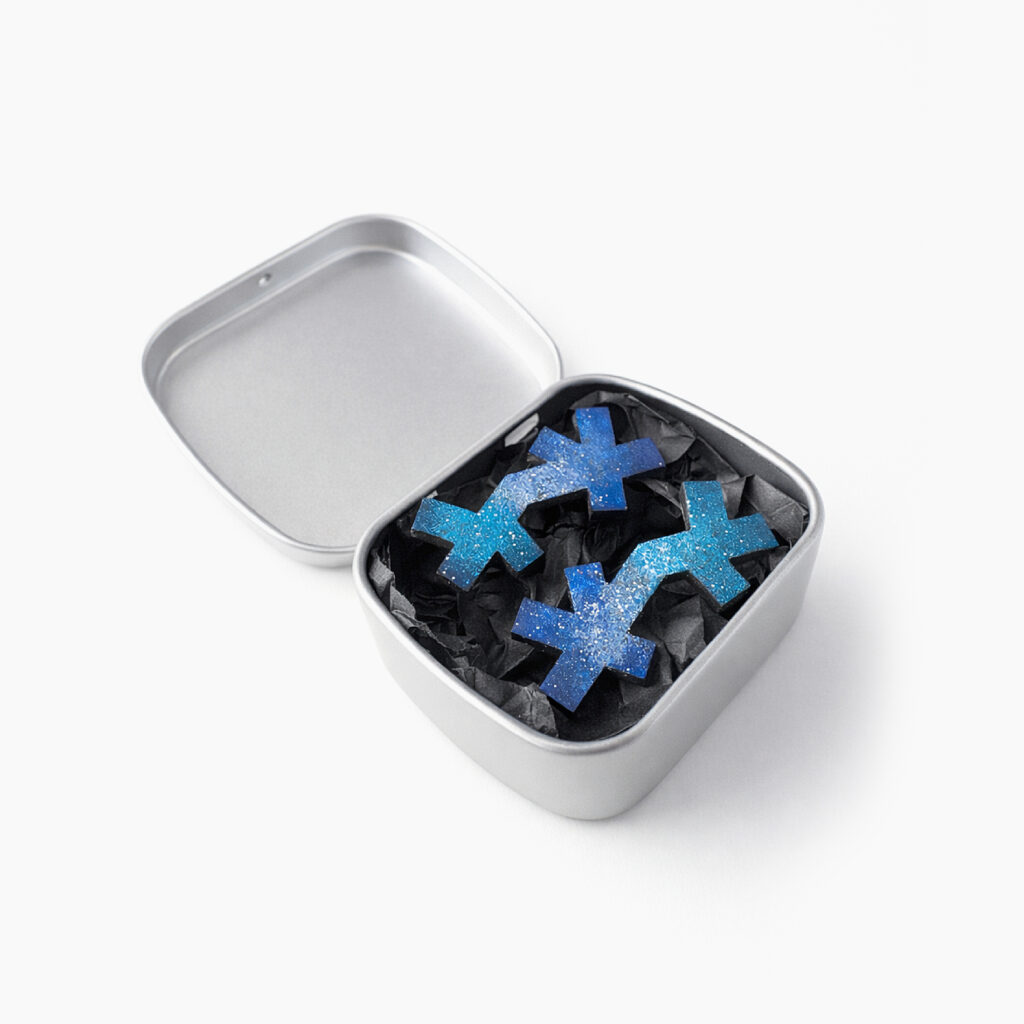 Blue geometric wooden stud earrings displayed in a metal gift box