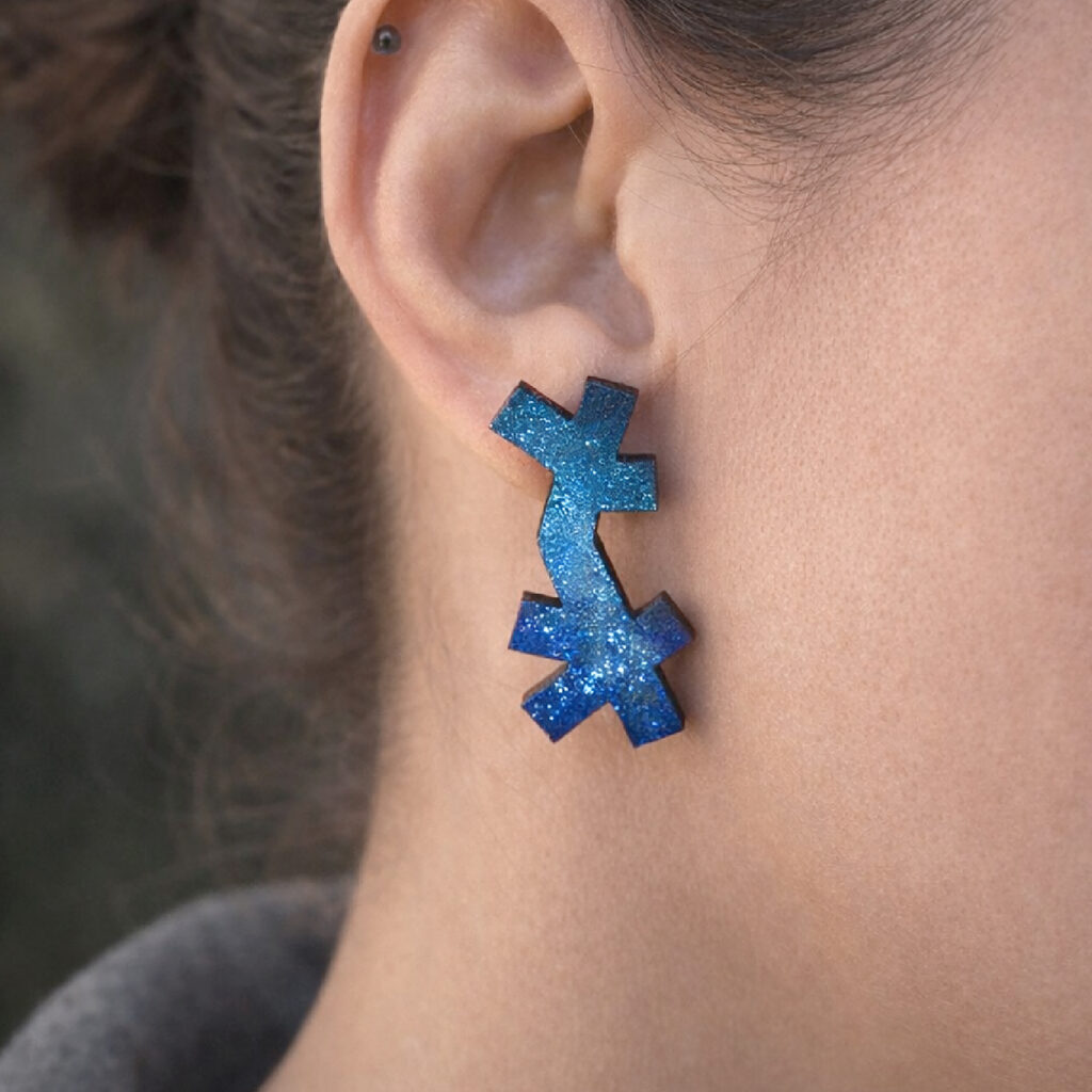 Blue abstract wooden stud earrings worn on ear – close-up