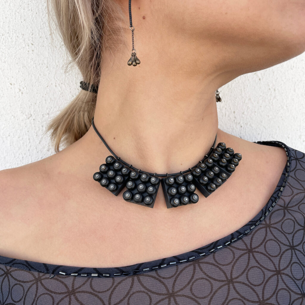 Black industrial geometric statement necklace worn around neck