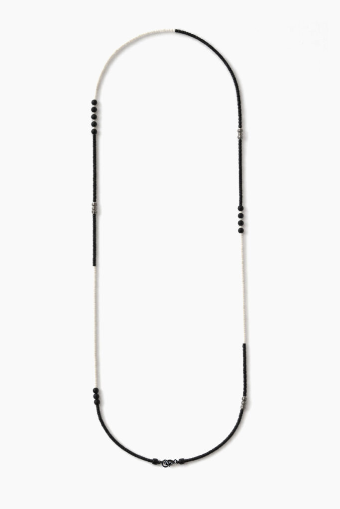 Long black and white minimalist beaded necklace on white background