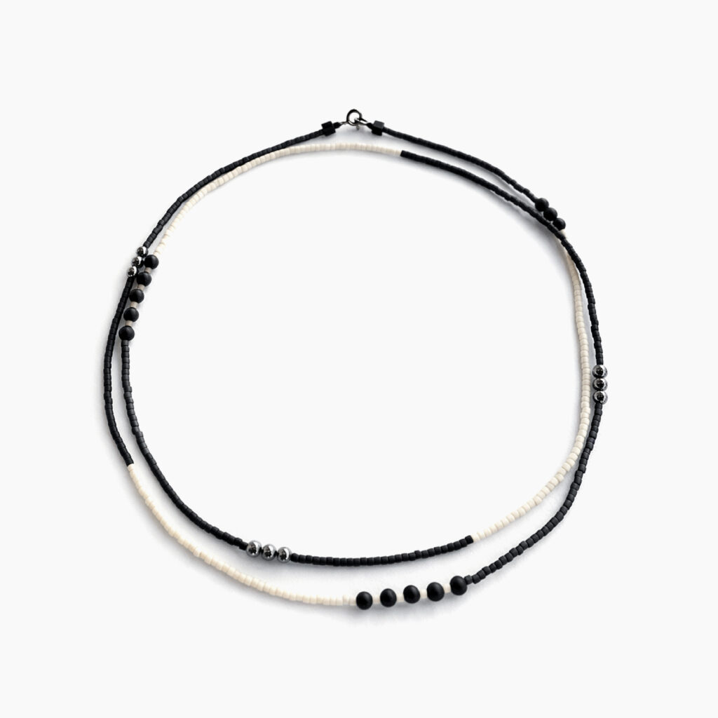 Black and white minimalist necklace arranged in a circle on a white background